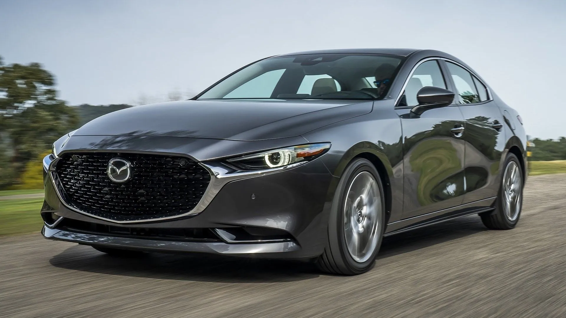 Mazda 3 Sedan 2019 màu xám bạc, với góc nhìn 3/4 phía trước, làm nổi bật thiết kế thanh lịch và hiện đại của dòng xe sedan cỡ nhỏ.