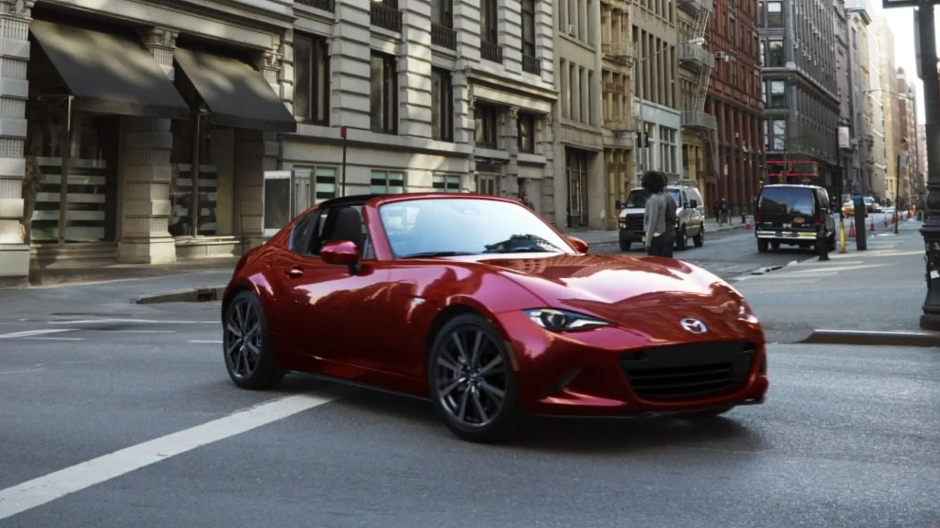 Mazda MX-5 RF 2025 màu đỏ lướt qua đường phố đô thị, minh họa khả năng tiết kiệm nhiên liệu