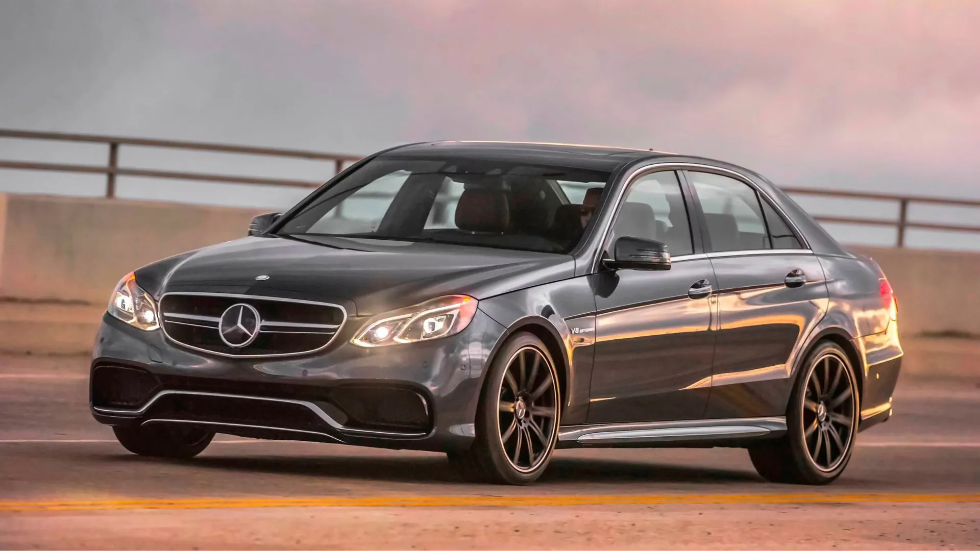 Mercedes-Benz E63 AMG 2015 màu xám bạc đang vượt qua cây cầu, thể hiện sự tinh tế trong vận hành