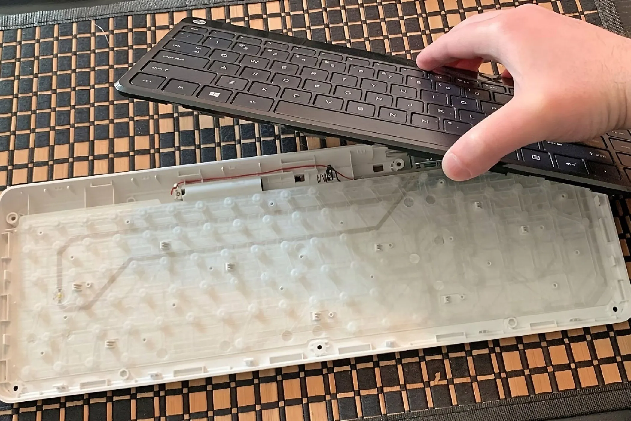 Một bàn phím màng đang được tháo rời, hiển thị tấm màng phím (membrane) và khu vực tiếp xúc cần được vệ sinh