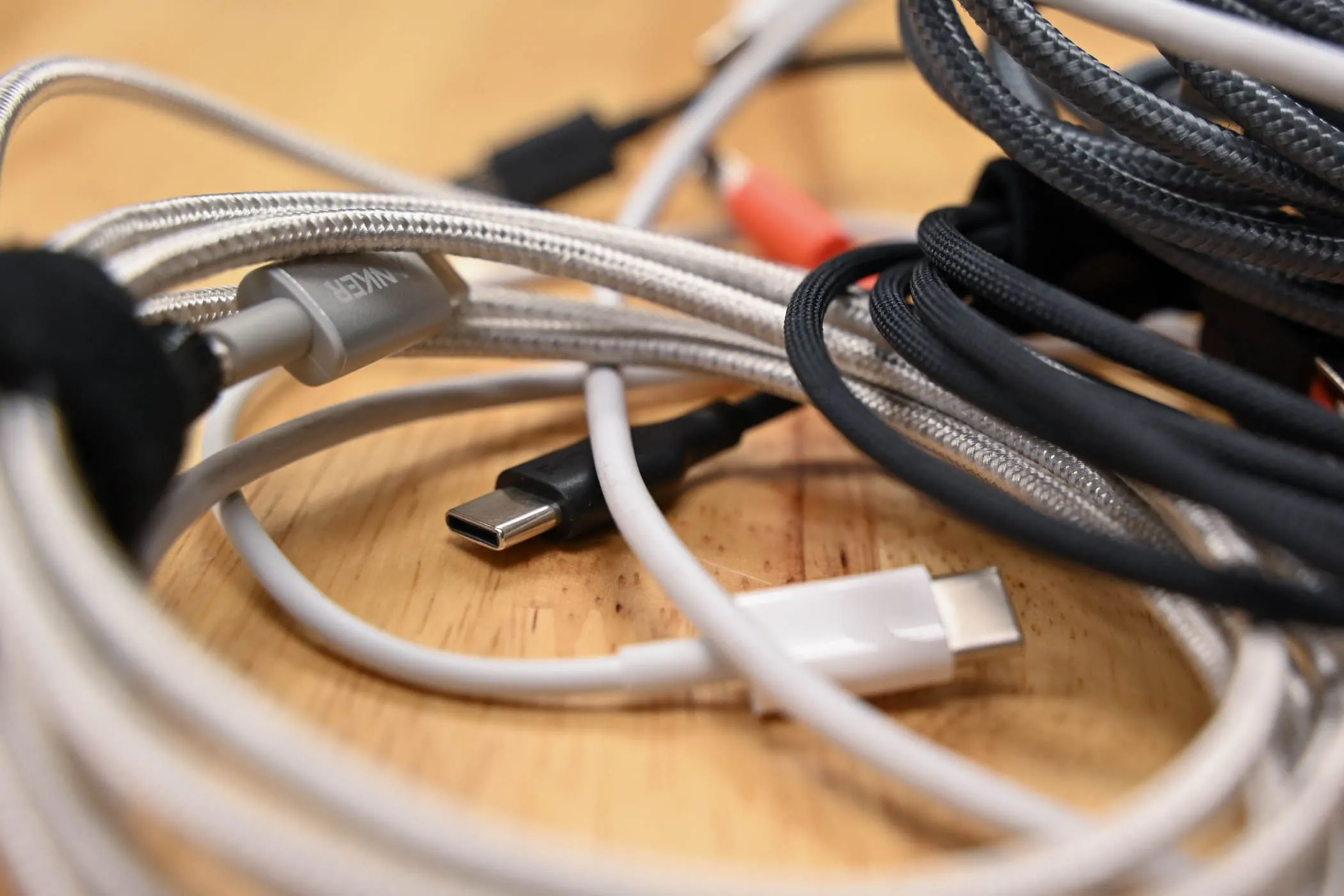 Một chồng cáp sạc USB-C đa dạng nằm trên bề mặt gỗ, minh họa tầm quan trọng của cáp sạc nhanh.