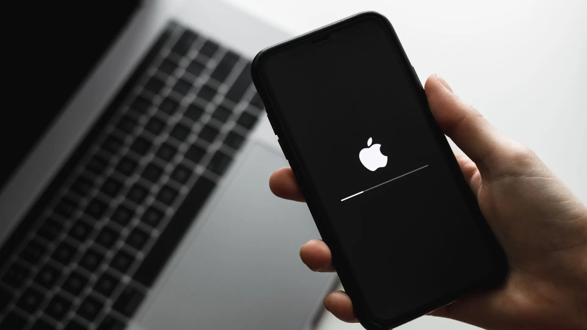 Một người đang cầm iPhone trong tay khi thiết bị đang tiến hành cập nhật phần mềm, nhấn mạnh khả năng cập nhật thường xuyên của ứng dụng định vị smartphone.