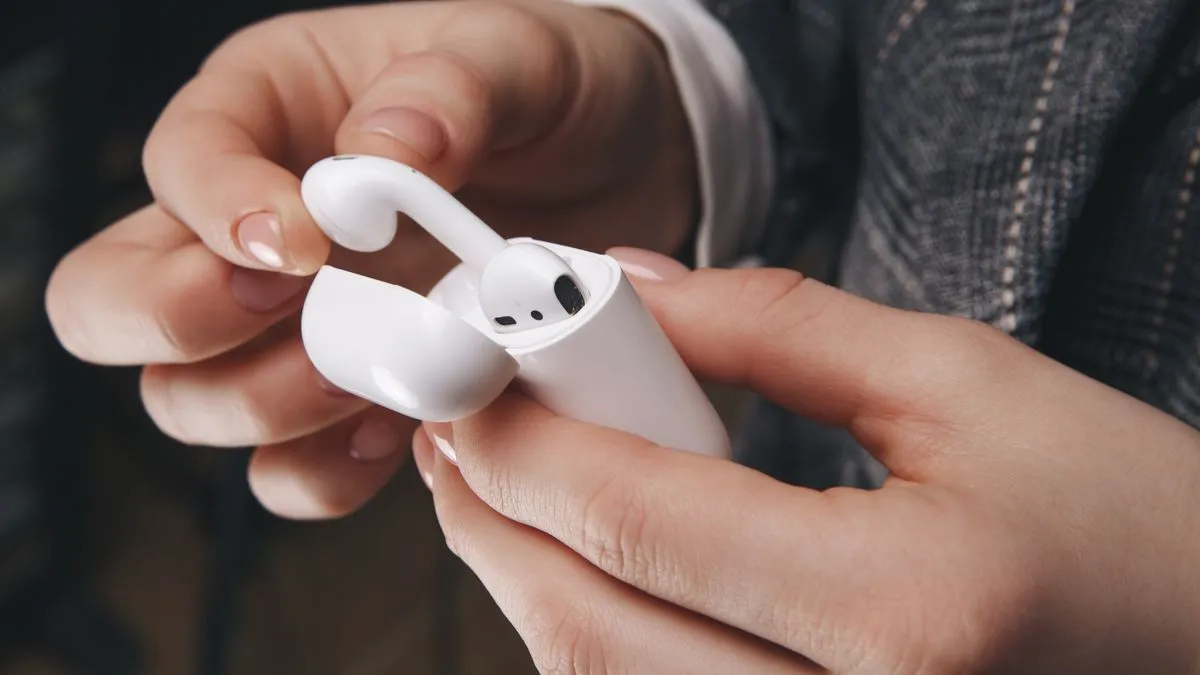 Một người đang lấy tai nghe AirPods ra khỏi hộp sạc của chúng