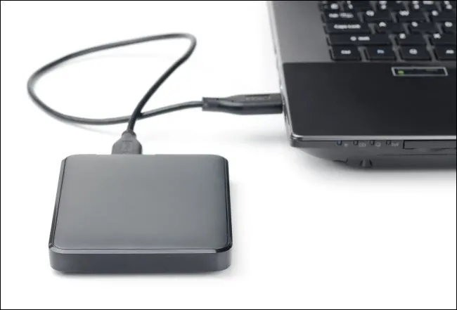 Một ổ cứng gắn ngoài (HDD) đang được kết nối với laptop qua cáp USB, minh họa thiết bị lưu trữ di động.