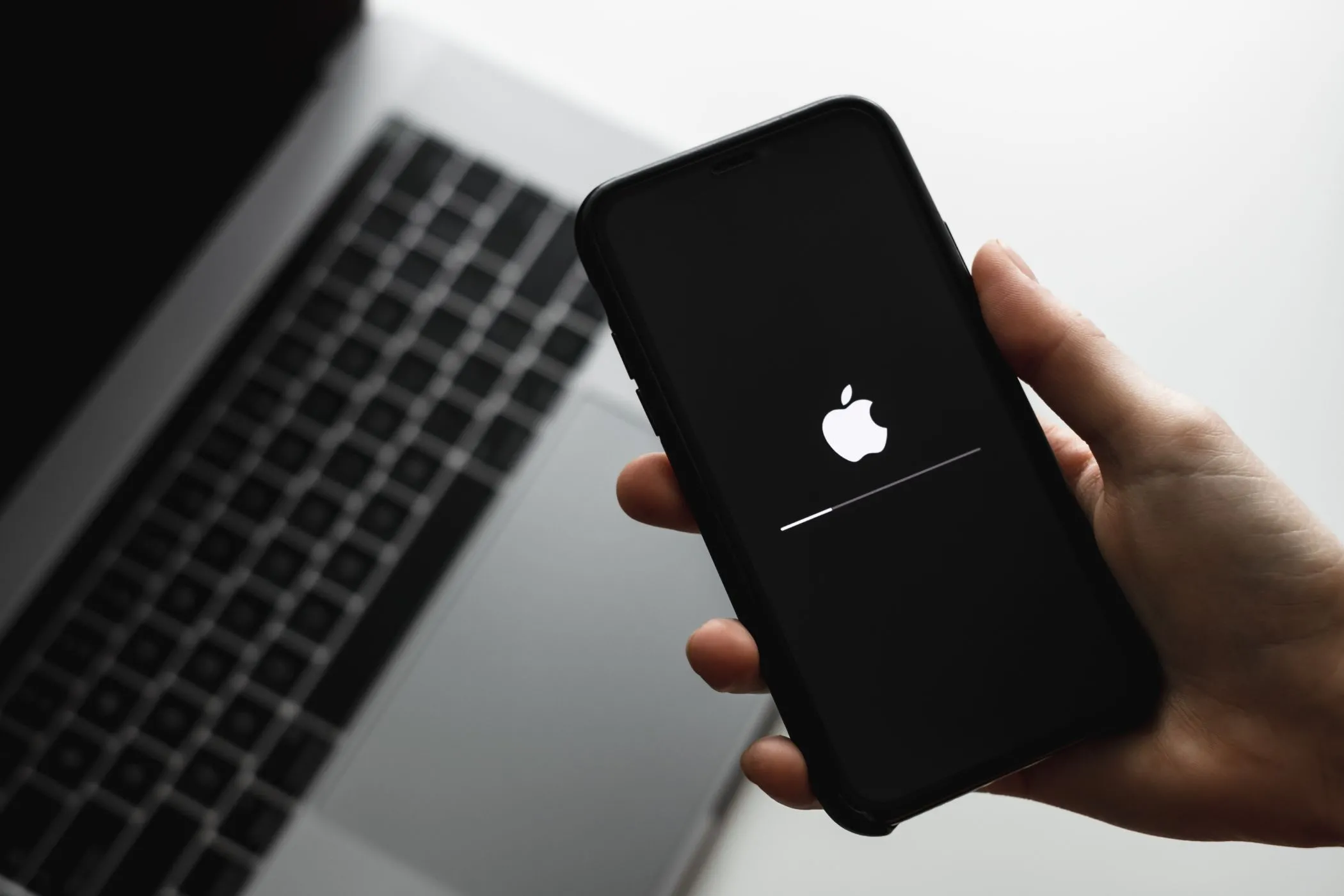 Người dùng đang cầm chiếc iPhone trong quá trình cập nhật phần mềm iOS, minh họa cho tầm quan trọng của các bản vá bảo mật và tính tương thích.