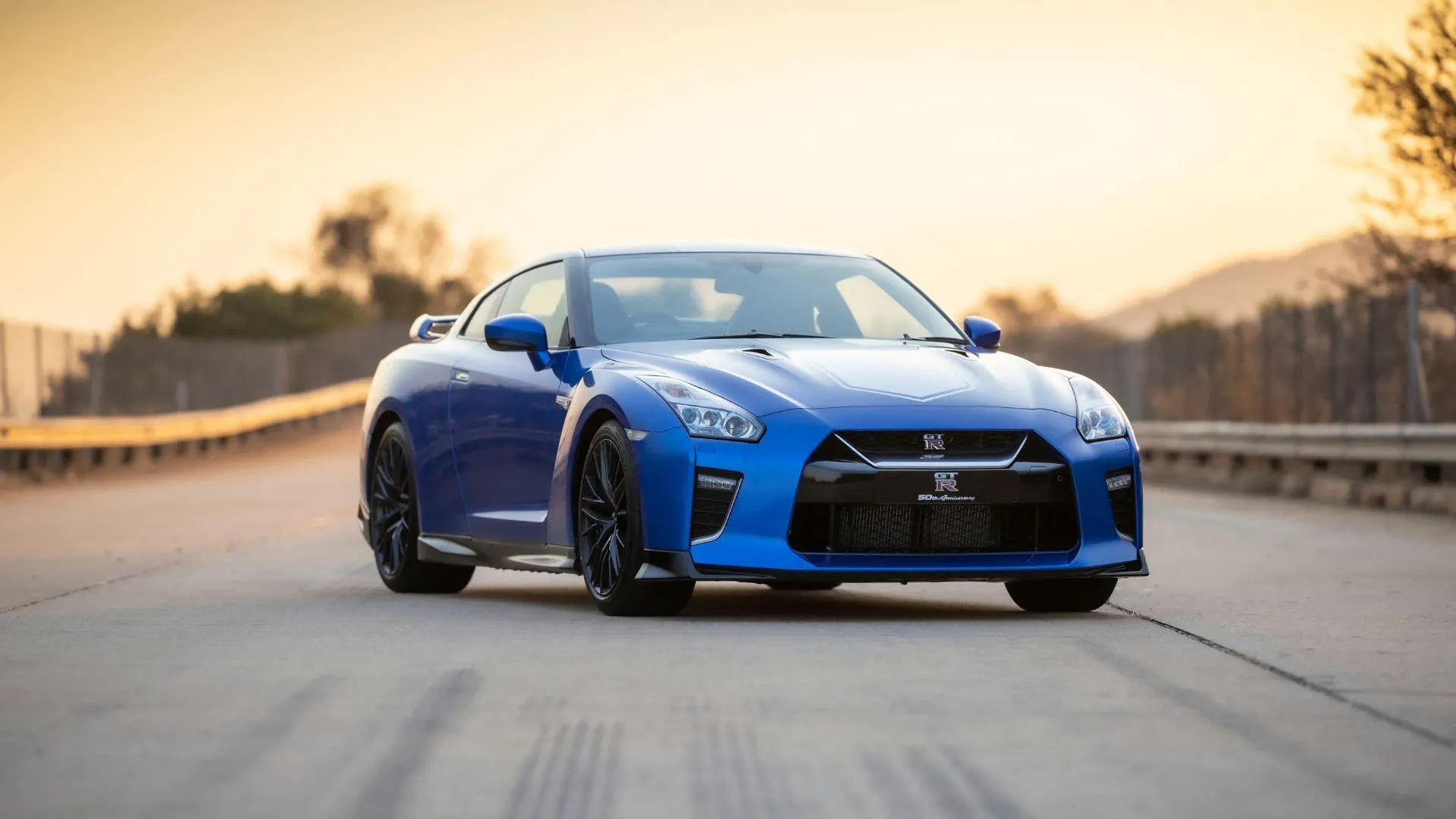 Nissan GT-R 50th Anniversary Edition 2020 màu xanh đậu trên đường nhựa, biểu tượng của hiệu suất xe thể thao Nhật Bản.