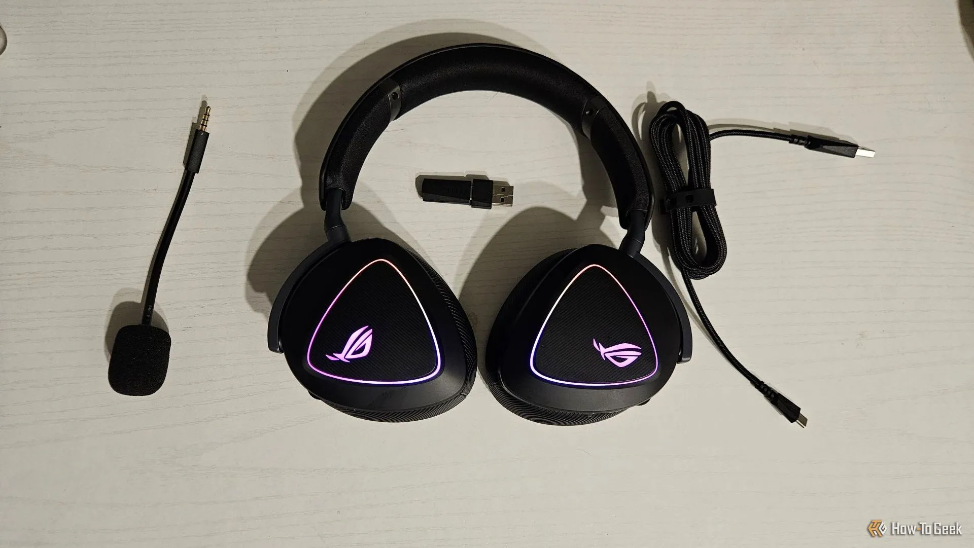 Tai nghe gaming ASUS ROG Delta II cùng các phụ kiện đi kèm như cáp sạc, micrô rời và đệm tai thay thế.