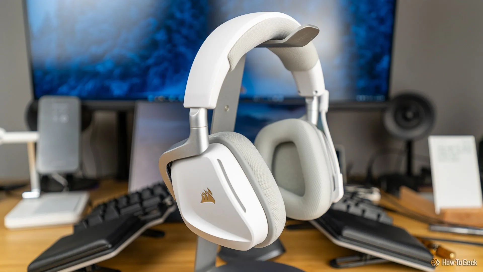 Tai nghe gaming Corsair Void Wireless V2 màu trắng đặt trên giá đỡ, giữa không gian gaming