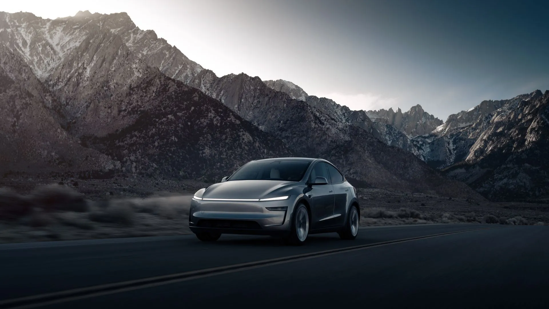 Tesla Model Y Long Range RWD 2025 màu xám bạc nổi bật trước khung cảnh núi non hùng vĩ, thể hiện sự tiện nghi và công nghệ tiên tiến.