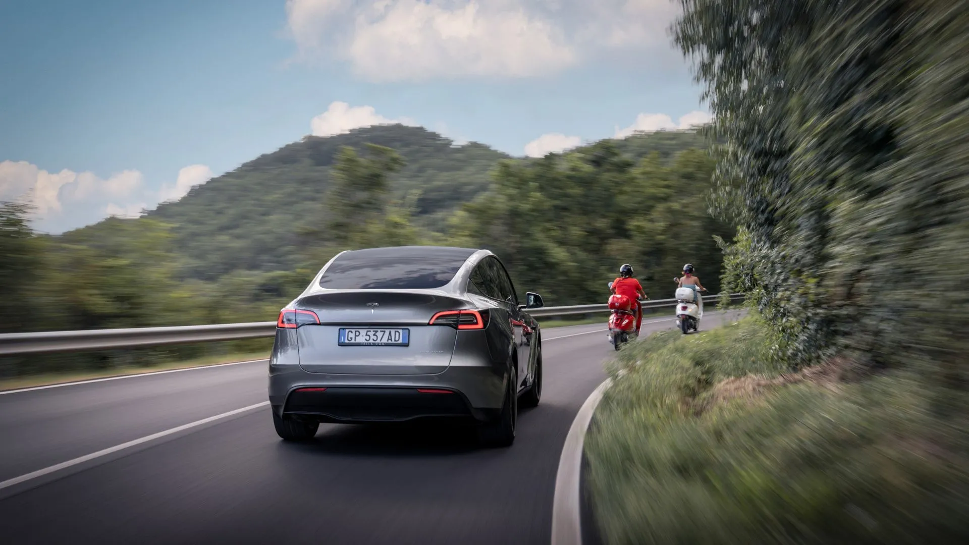 Tesla Model Y màu bạc vận hành trên đường đồi núi, minh họa khả năng di chuyển và tuổi thọ pin của xe điện.