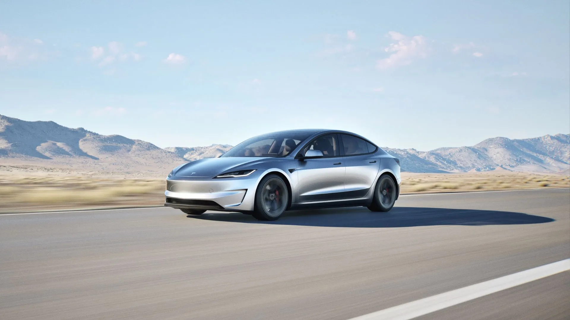 Toàn cảnh chiếc Tesla Model 3 Performance màu bạc đang lái trên đường nông thôn với núi non hùng vĩ phía sau, minh họa cho hiệu suất và thiết kế hiện đại của phiên bản 2025.