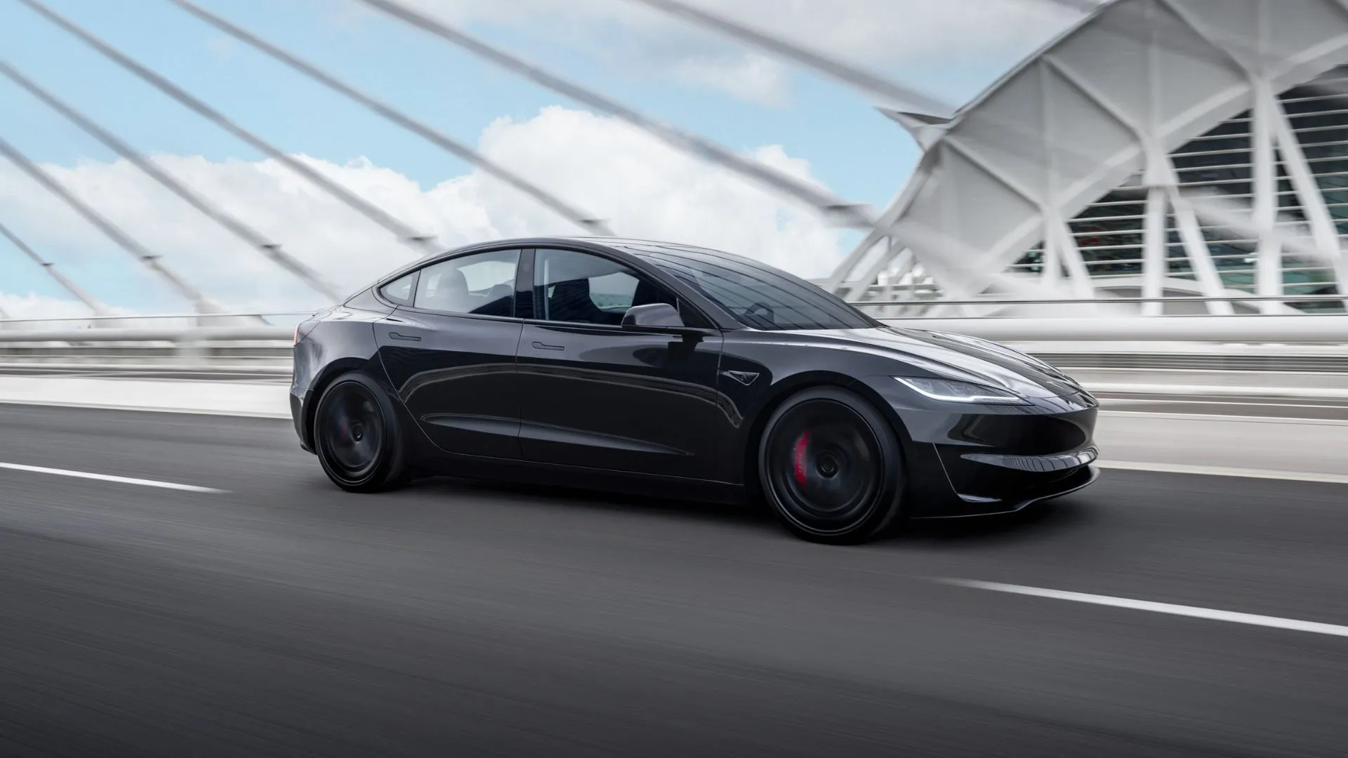 Toàn cảnh chiếc Tesla Model 3 Performance màu đen đang lái qua cầu trong một thành phố sầm uất, khẳng định khả năng vận hành bền bỉ và rộng khắp của dòng xe điện này trên nhiều địa hình.