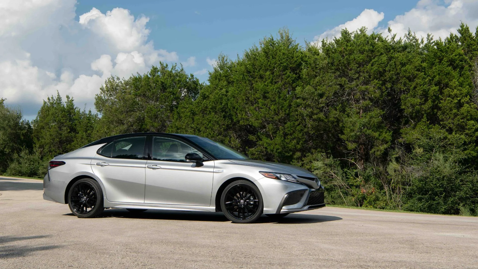 Toàn cảnh Toyota Camry Hybrid 2022 XSE màu bạc đỗ trên nền nhựa đường, nổi bật với thiết kế hiện đại và sang trọng.