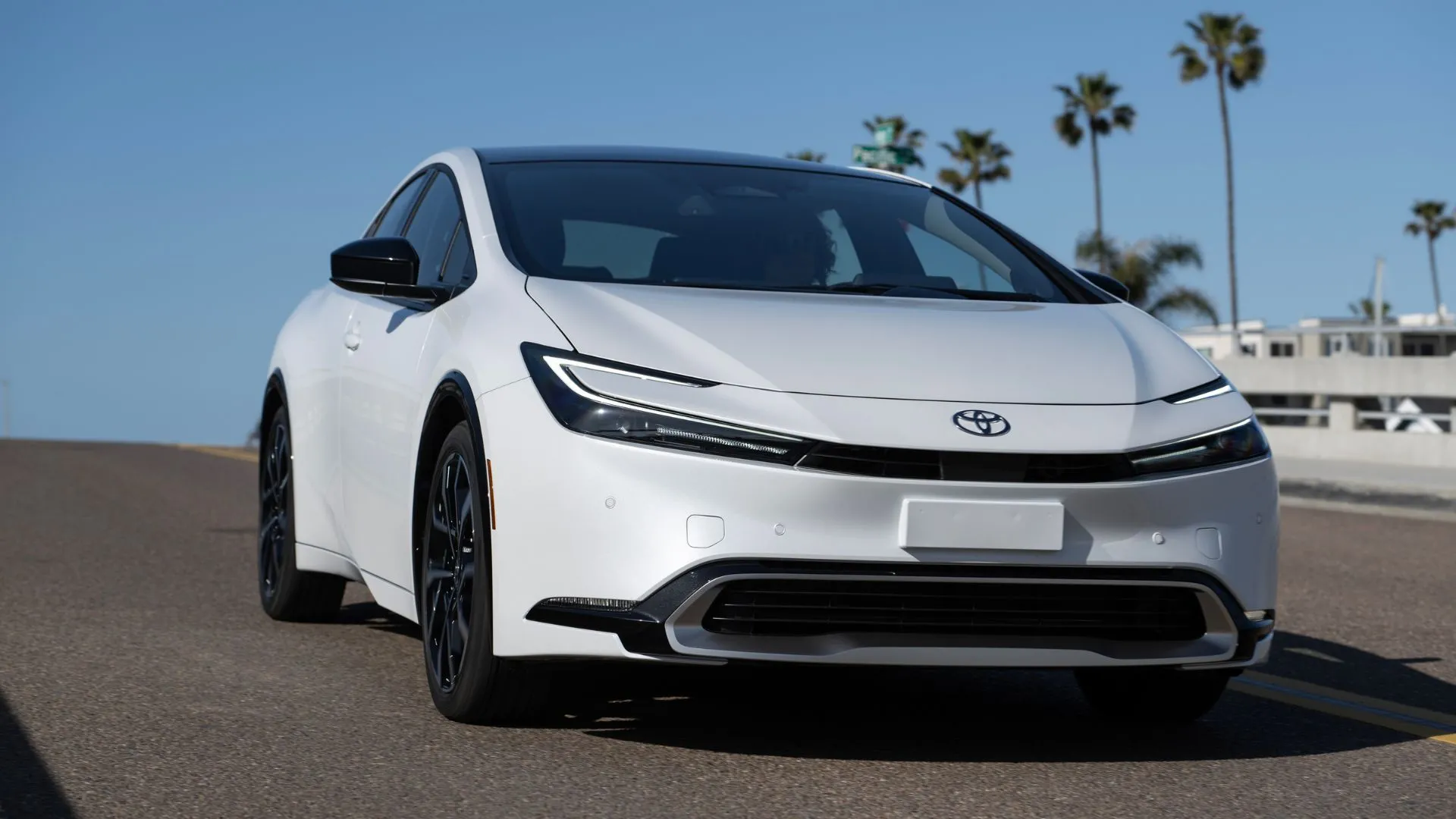 Toyota Prius PHEV XSE 2025 màu trắng đang lái qua cầu.