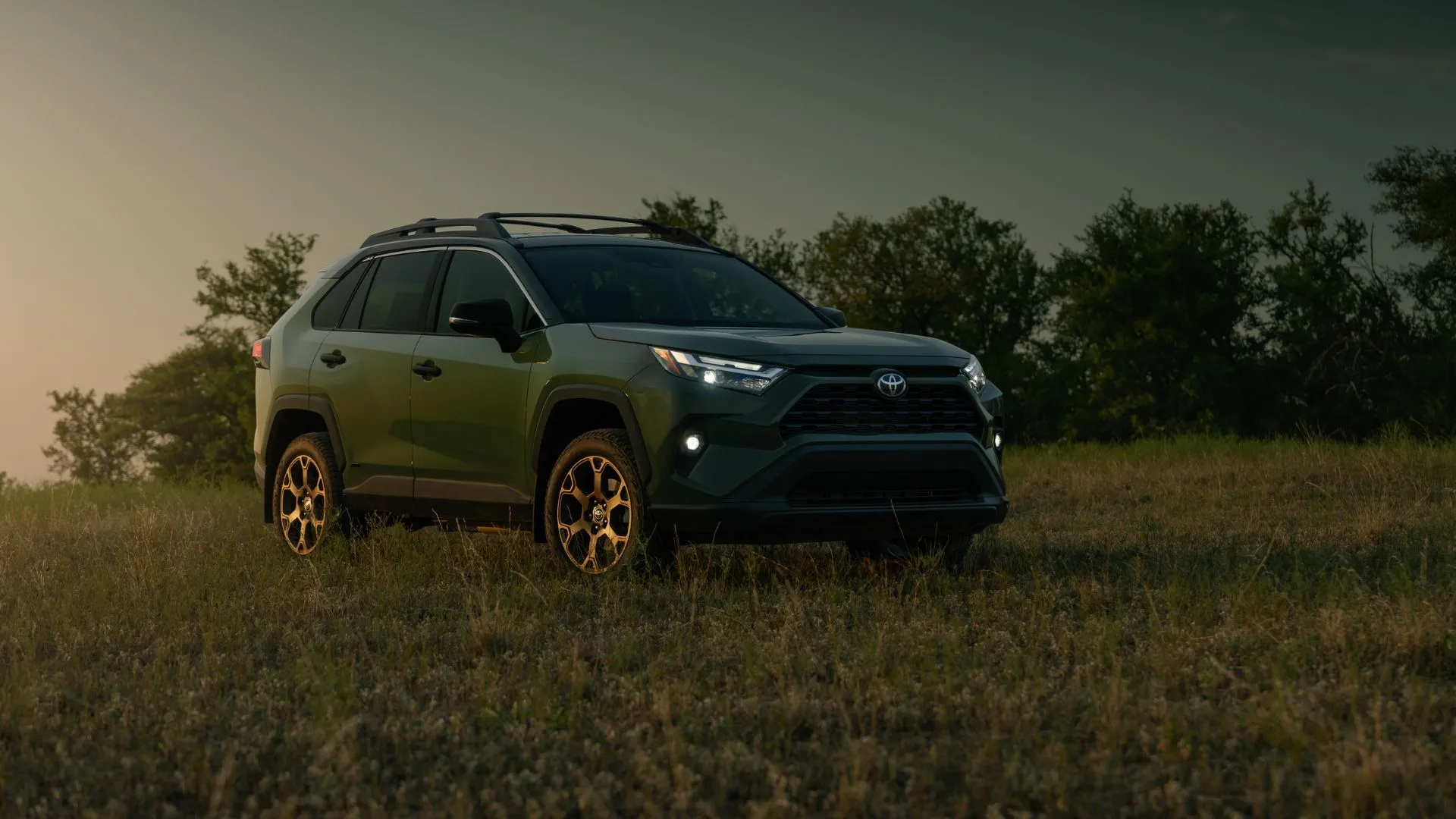 Toyota RAV4 Hybrid 2024 màu xanh quân đội đỗ trên bãi cỏ, SUV hybrid linh hoạt và tiết kiệm nhiên liệu