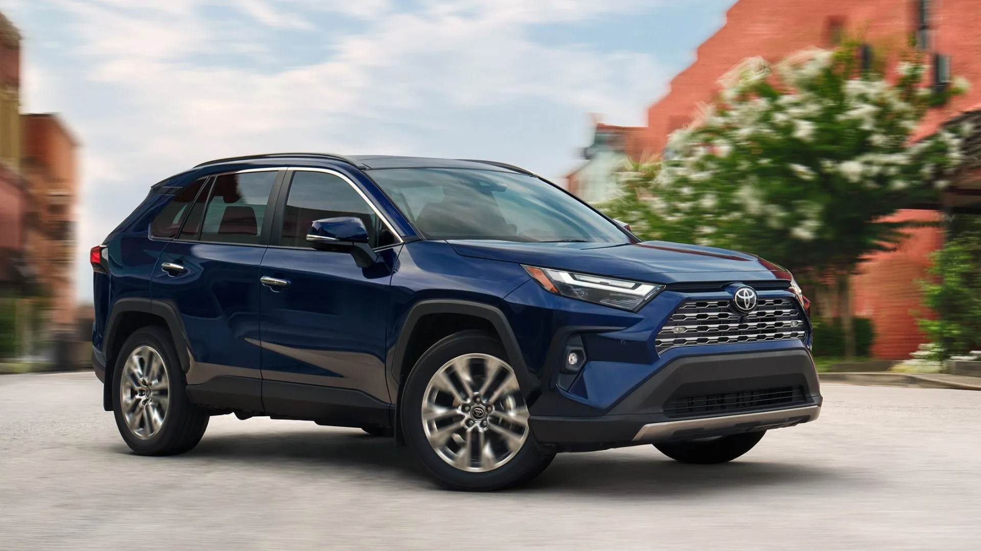 Toyota RAV4 LE 2025 màu xanh năng động di chuyển trên đường phố, biểu tượng của sự linh hoạt và tiện dụng cho đô thị.