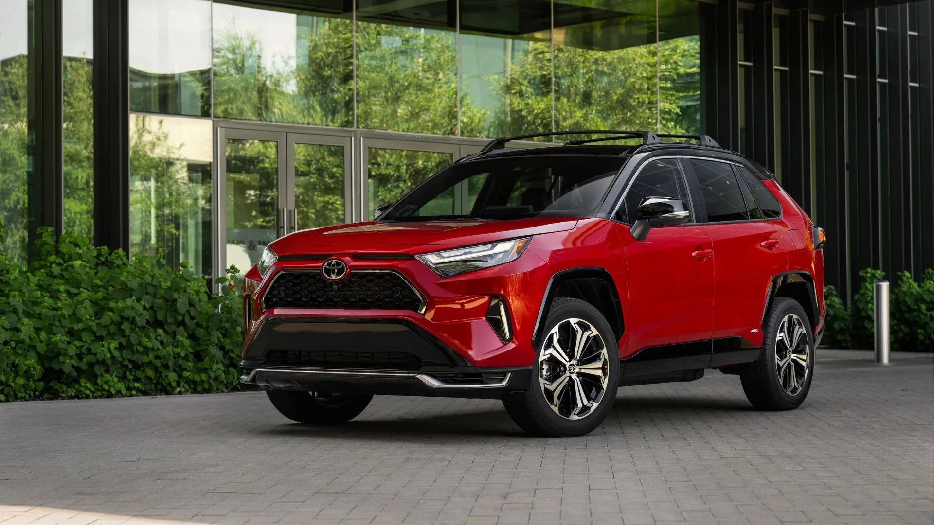 Toyota RAV4 PHEV XSE 2025 màu đỏ đậu trước tòa nhà hiện đại.