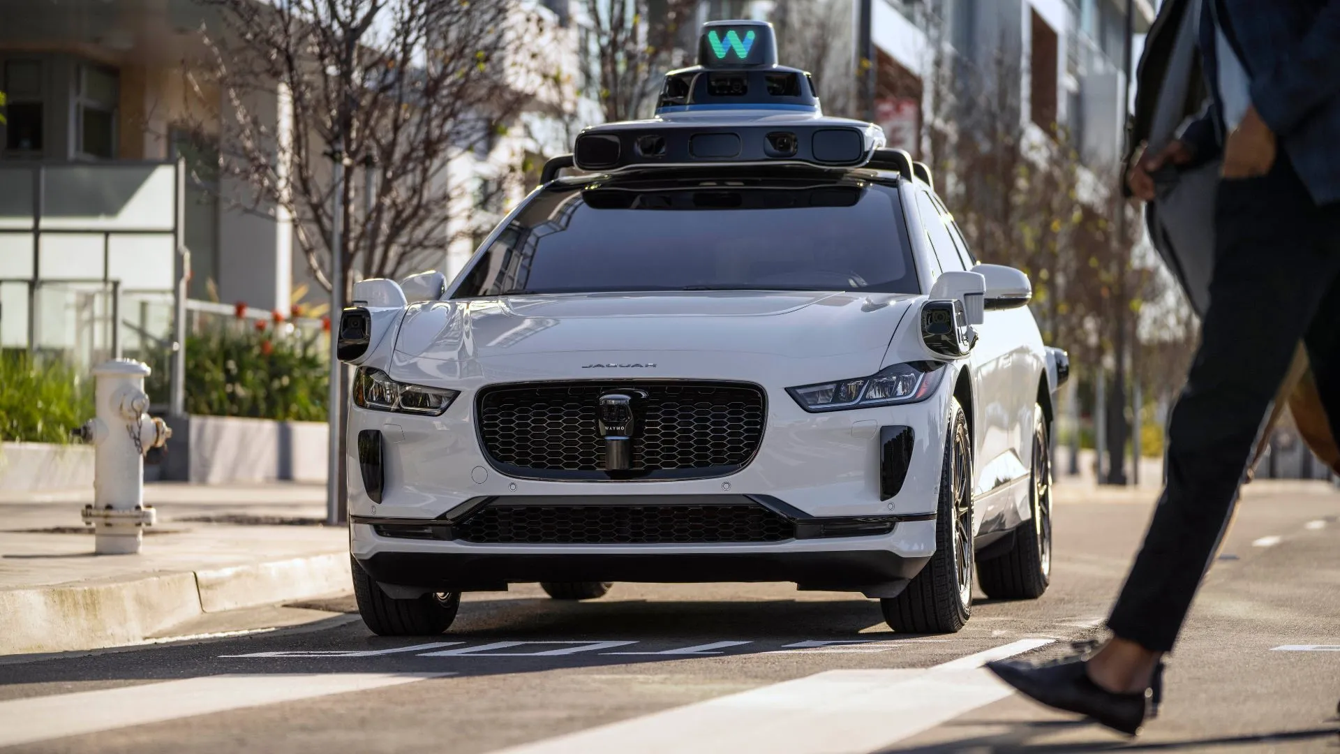 Xe tự lái Waymo Jaguar I-PACE dừng nhường đường cho người đi bộ, minh họa công nghệ AI và LiDAR.