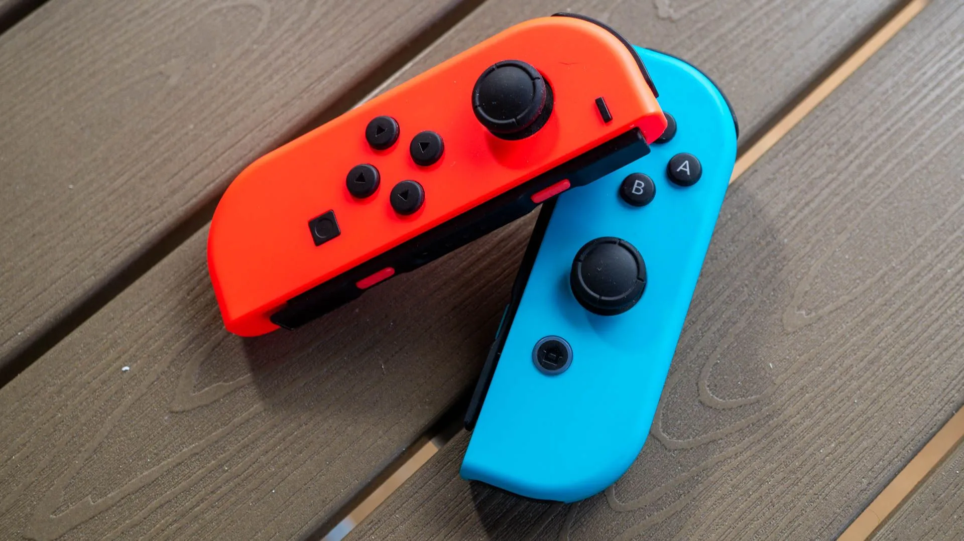 Cặp tay cầm Joy-Con màu đỏ và xanh của Nintendo Switch trên bàn gỗ, gợi ý về các trình giả lập console hiện đại.