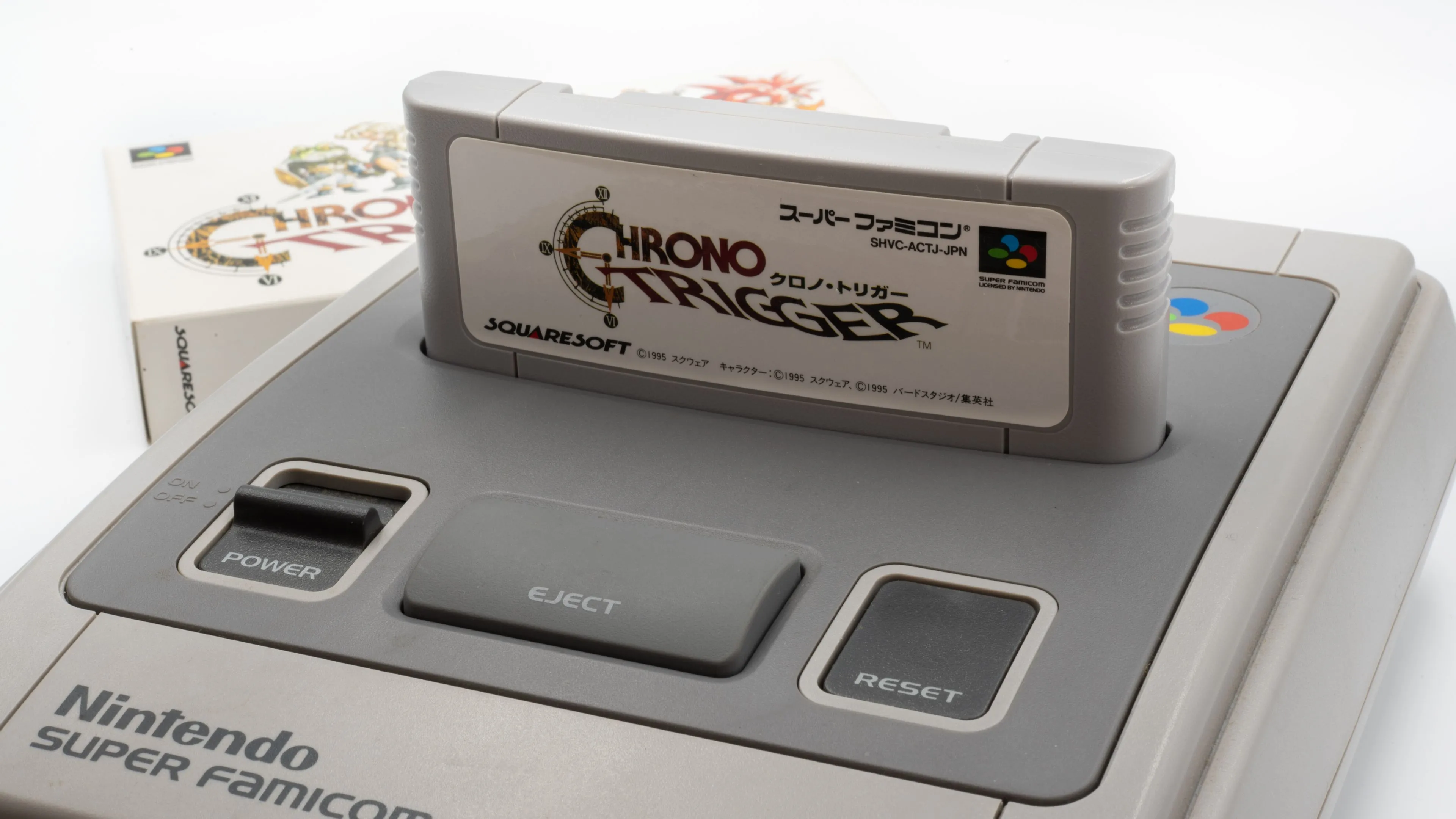 Hộp băng game Chrono Trigger huyền thoại được cắm vào máy chơi game Super Famicom (SNES) cổ điển, thể hiện sự khao khát phần cứng gốc.