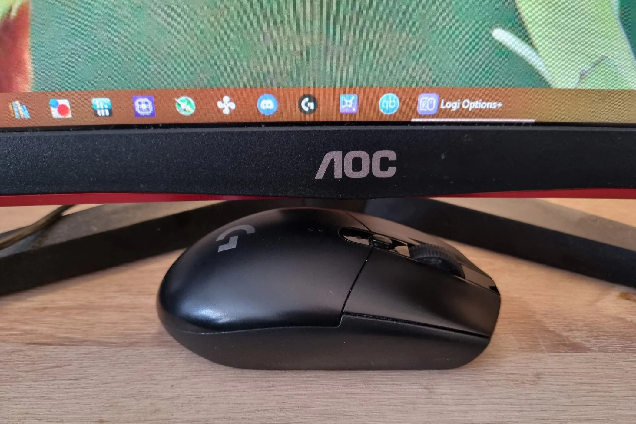 Chuột gaming không dây Logitech G305 đặt gọn gàng dưới màn hình, thể hiện sự tiện lợi của chuột không dây.