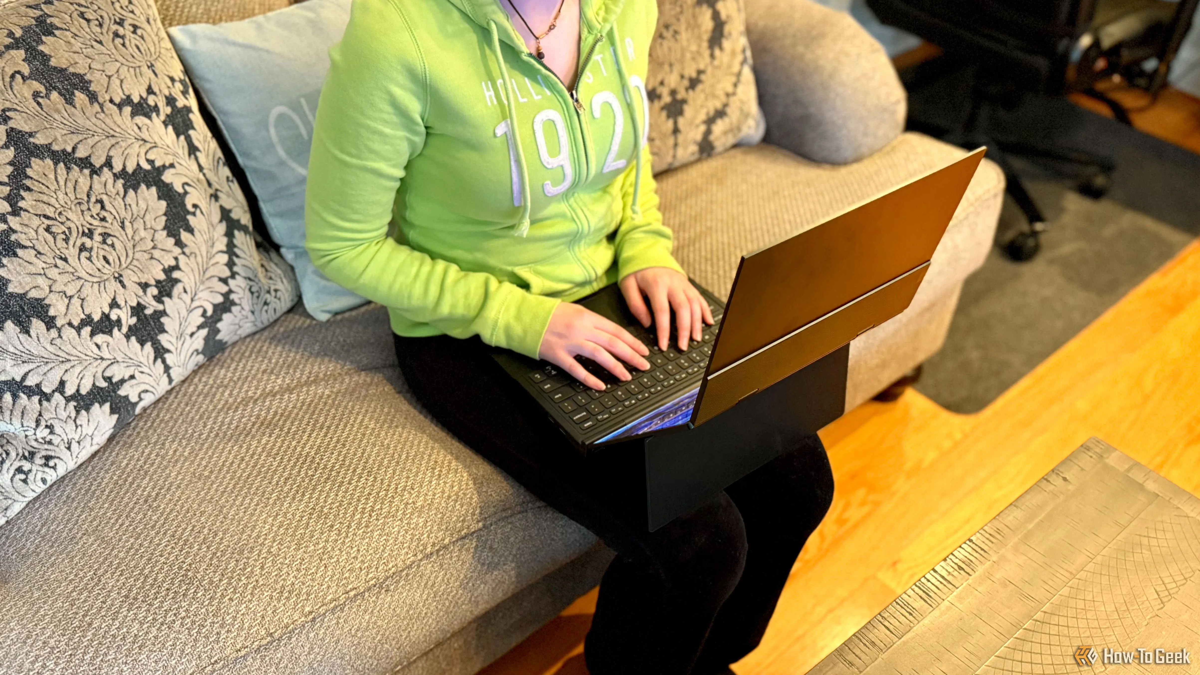 Một người phụ nữ ngồi trên ghế sofa sử dụng GPD Duo trên đùi, thể hiện tính di động và khả năng làm việc thoải mái