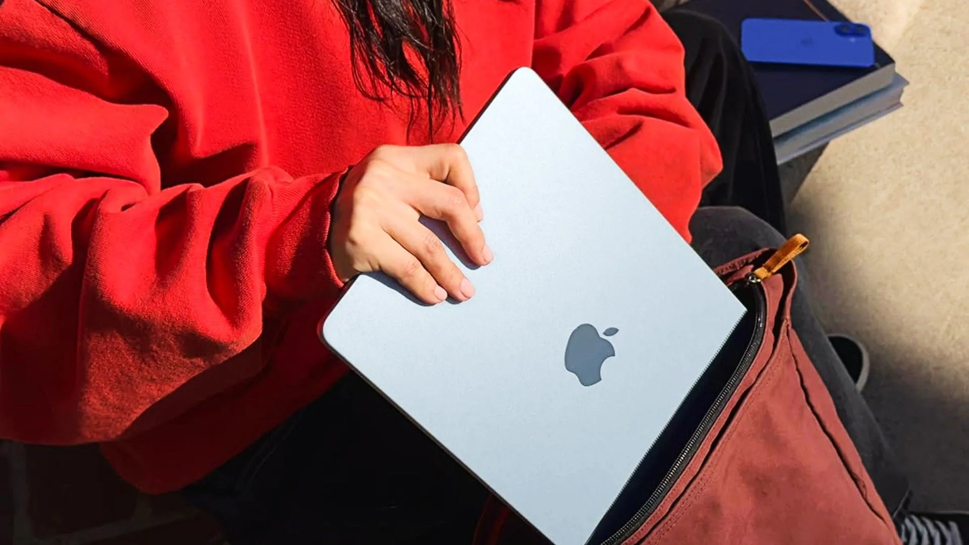 Người dùng đang đặt chiếc MacBook Air M4 vào túi xách, thể hiện tính di động và thiết kế cao cấp của dòng MacBook Air