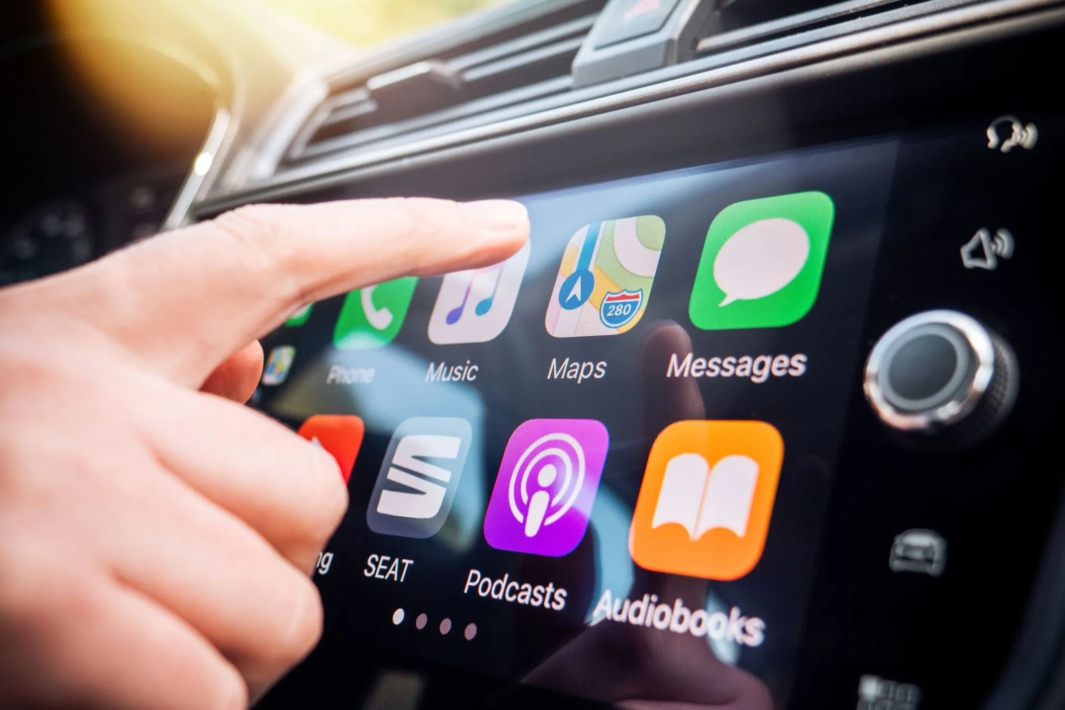 Người dùng tương tác với hệ thống Apple CarPlay tích hợp trên màn hình ô tô, thể hiện trải nghiệm lái xe hiện đại.